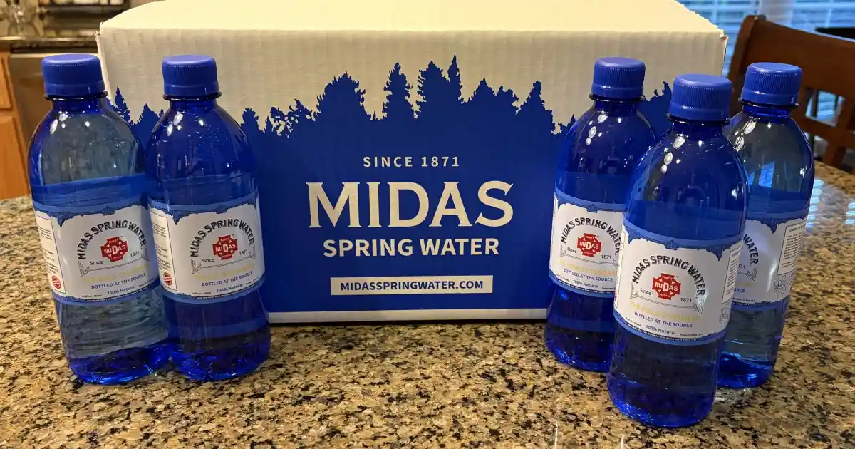  A box of Midas Spring Water and 5 500 ml bottles of Midas Spring Water sitting on a kitchen countertop