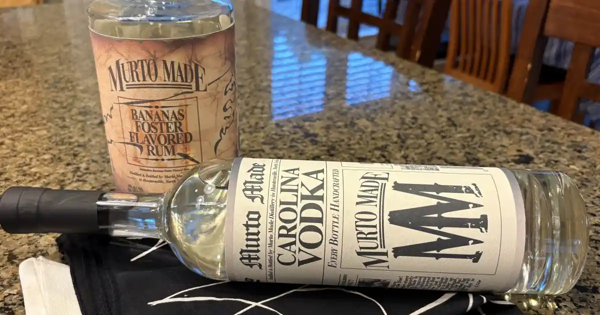 A bottle of Murto Made Bananas Foster Flavored Rum and a bottle of Murto Made Carolina Vodka on a kitchen countertop