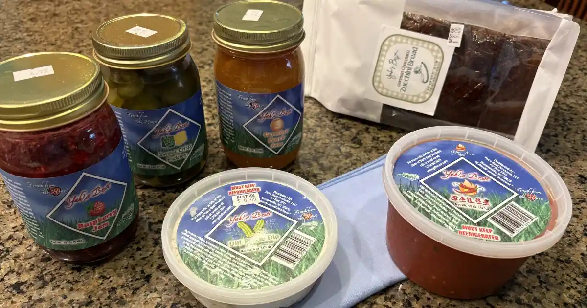Six products on a kitchen countertop made by Yah's Best Products - jars of salsa, jam, dip, and baked goods