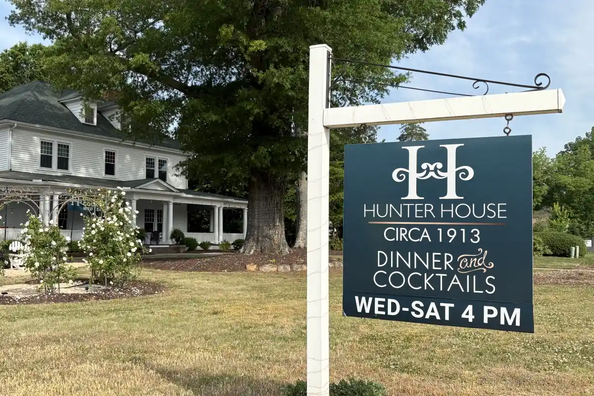 Exterior sign of Hunter’s House with historic building in the background