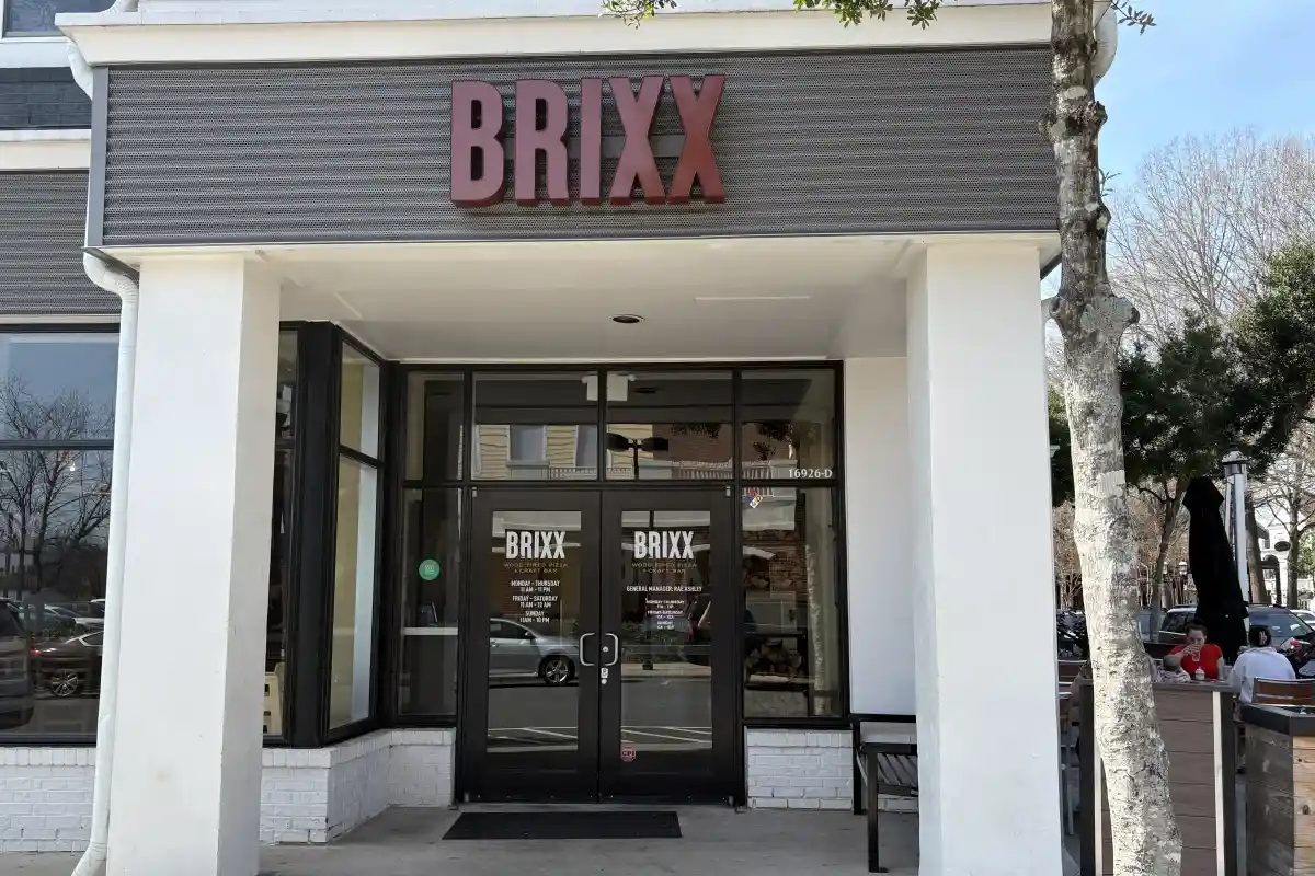 Front entrance to Brixx with signage and outdoor seating on the side