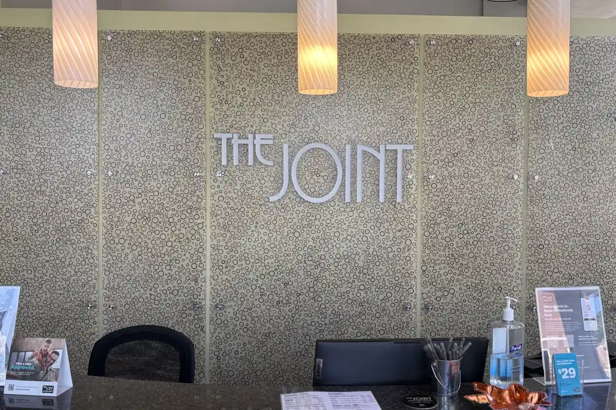 Branded sign behind the reception desk at The Joint Chiropractor