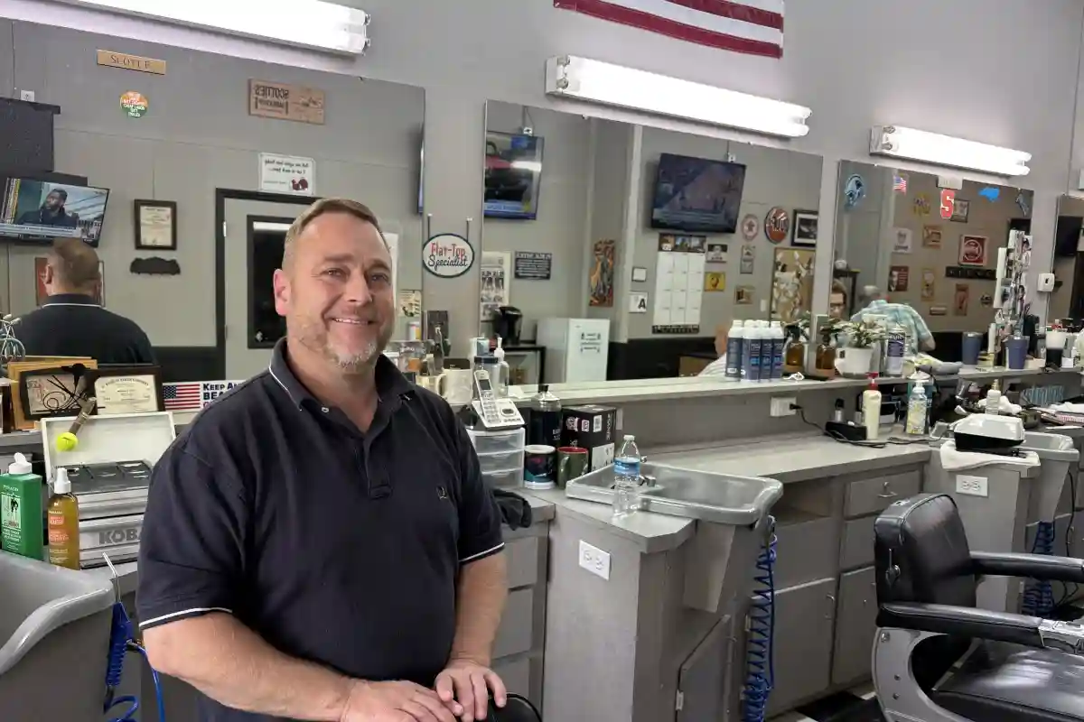 Owner of Scottie's Barber Shop, Scott Enloe, standing behind his barbers chair