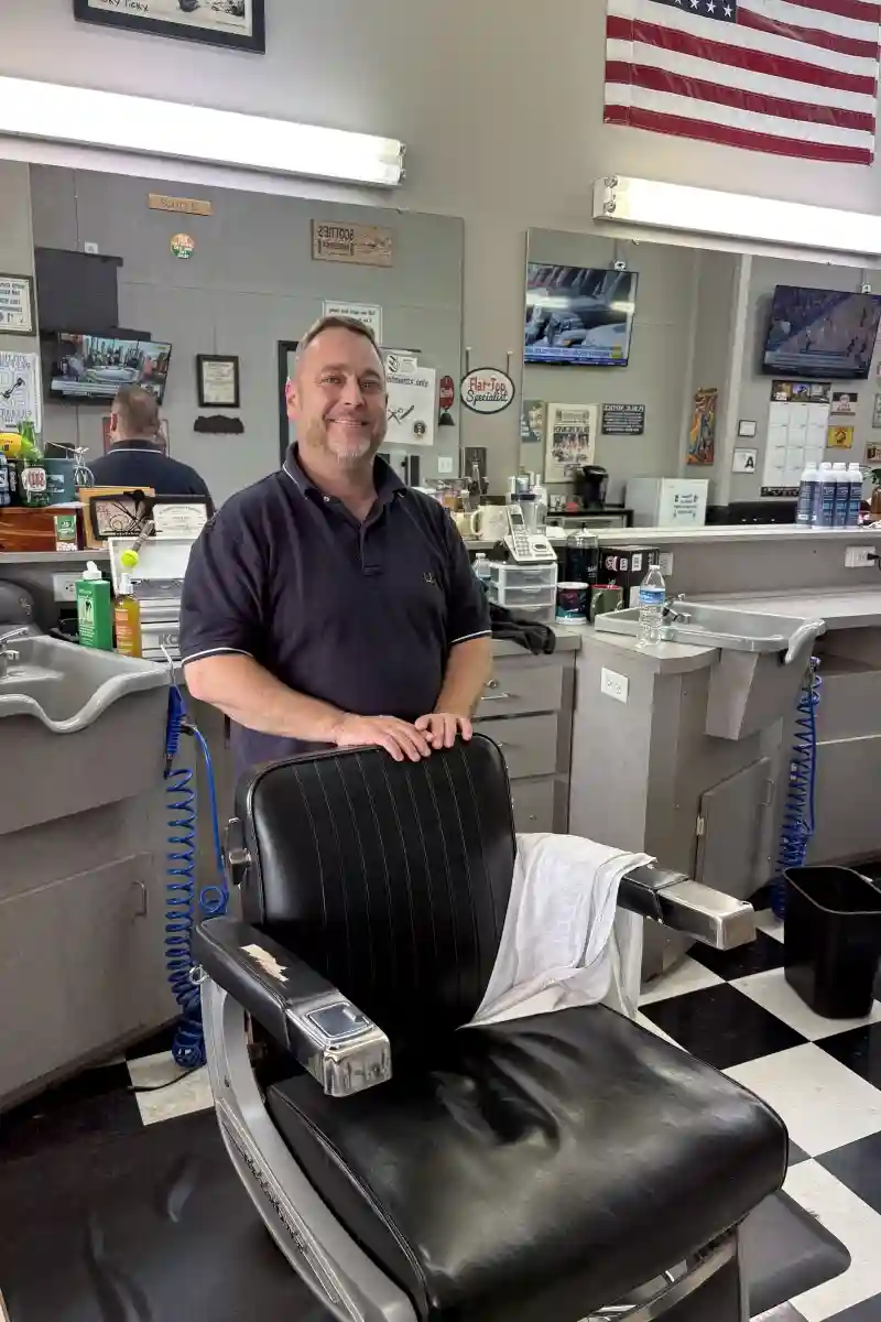 Scott Enloe owner of Scottie's Barber Shop standing at his barber chair