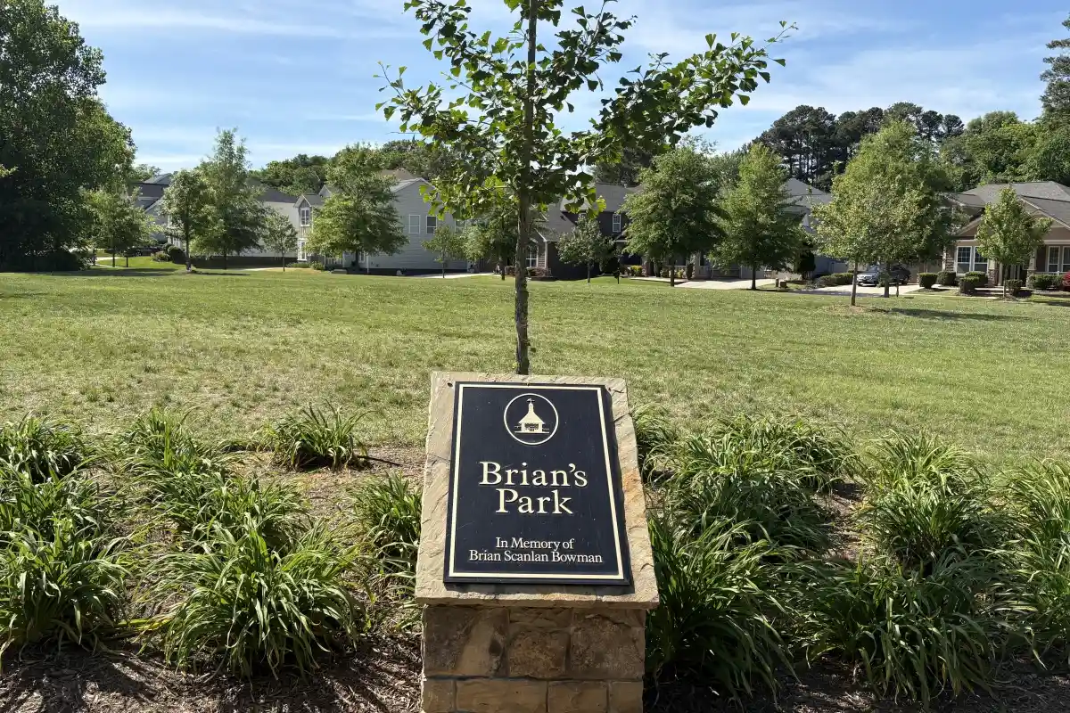 Brian S. Bowman Park in Huntersville, North Carolina with open lawn space, trees, and a memorial park sign