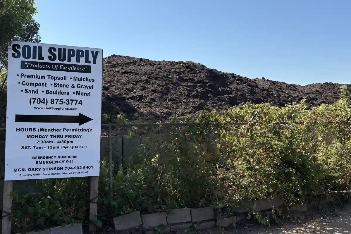 Sign for Soil Supply with pile of mulch behind a fence