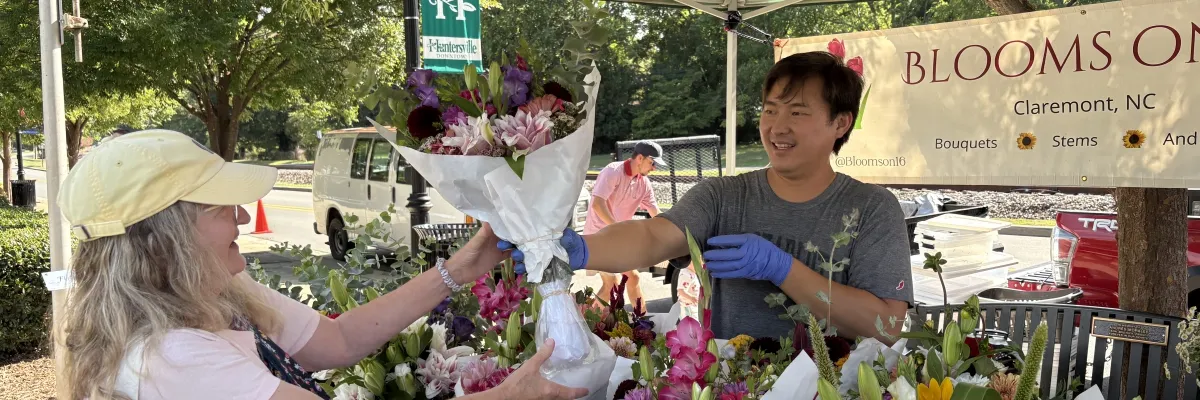 Blooms on 16 vendor handing a customer a fresh flower bouquet at the Huntersville Growers' Market