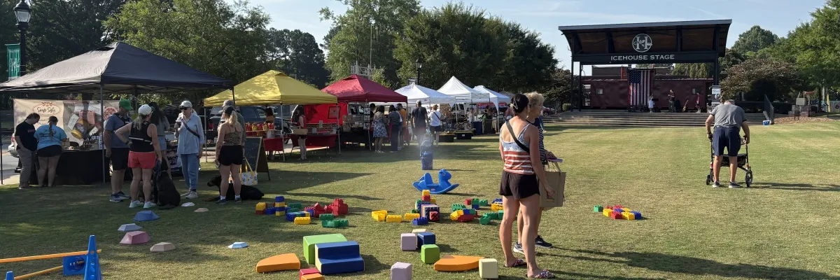 Families and kids enjoying the open lawn at the Huntersville Growers' Market near the Icehouse Stage