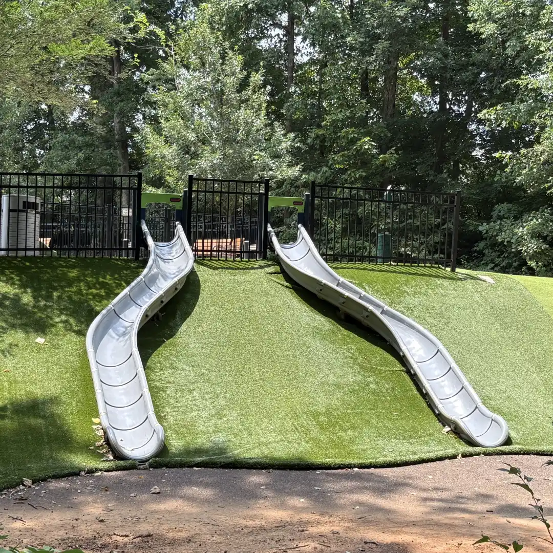 Two slides built into a grassy hillside in the natural play area at Rosedale Nature Park