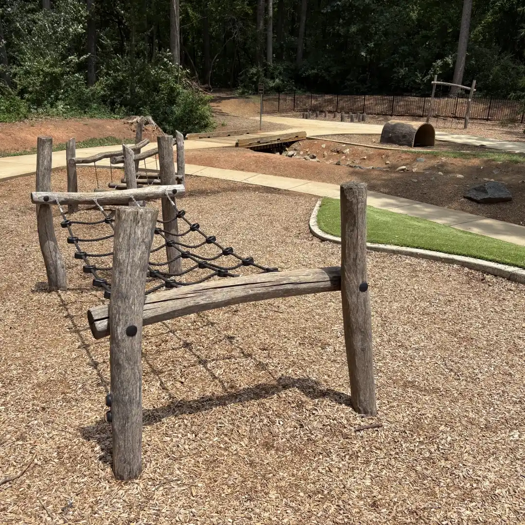 Rope climbing obstacle in the natural play area at Rosedale Nature Park, with a tunnel in the background