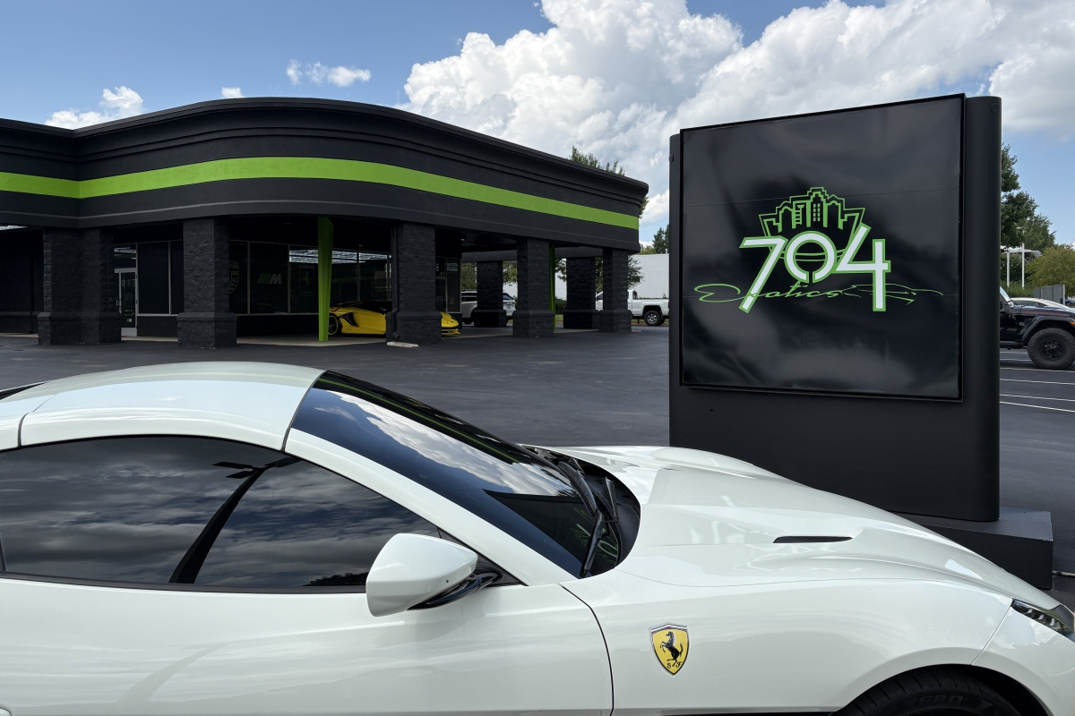 Sign for 704 Exotics with a Porche in the foreground