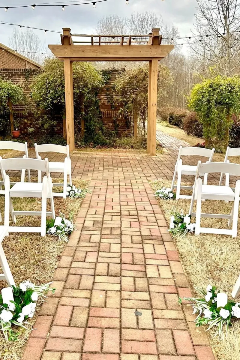 Ceremony aisle in the garden at Magnolia Woods, with a wooden arbor and brick path