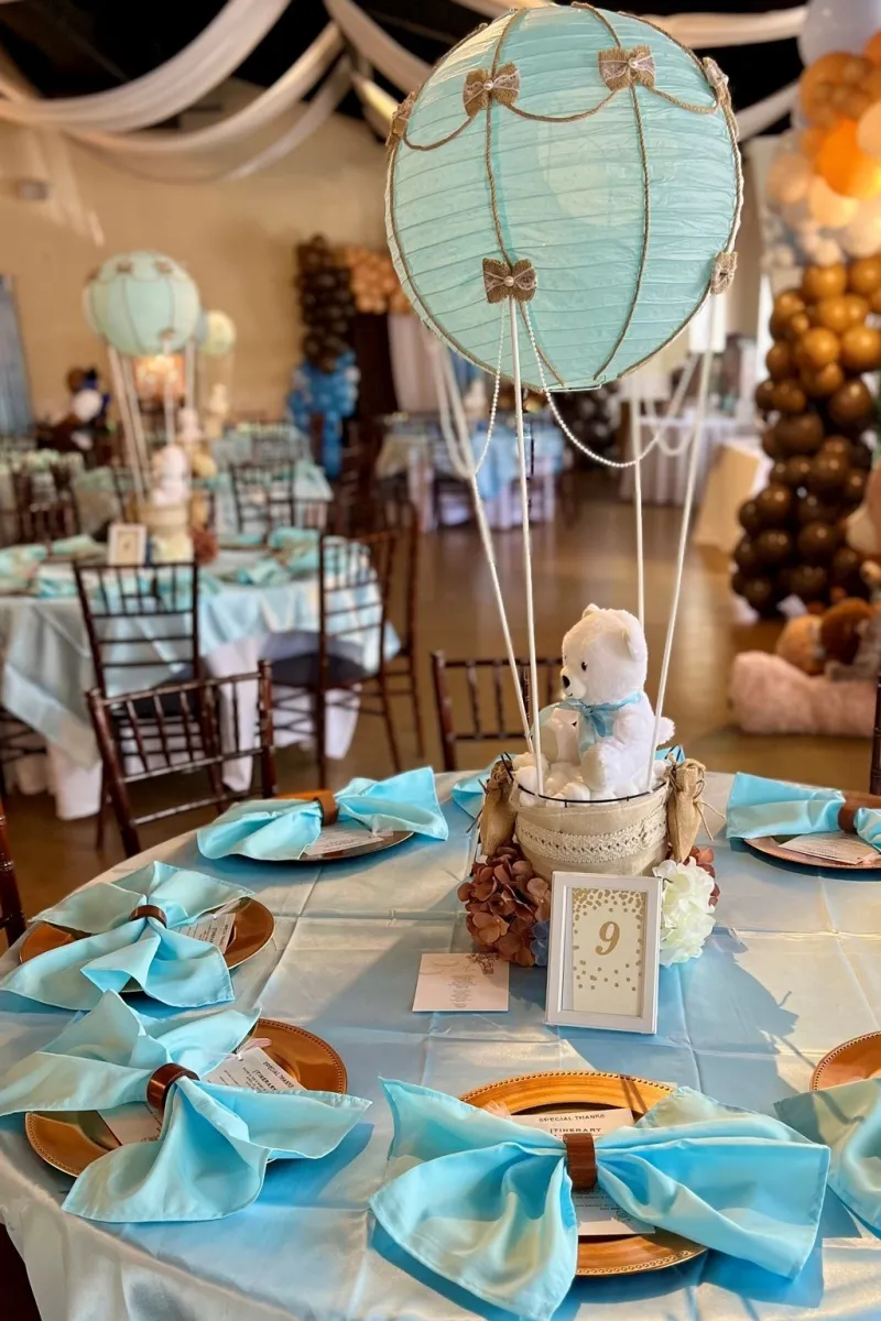Table setting with a hot air balloon centerpiece at a baby shower