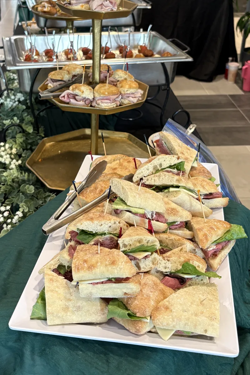 Tiered stand with ham biscuit sliders and sandwich platter from Savory Moments Catering