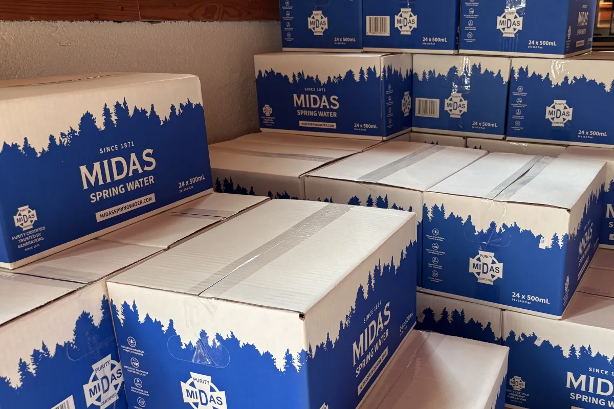 Stacked cases of Midas Spring Water bottles in storage