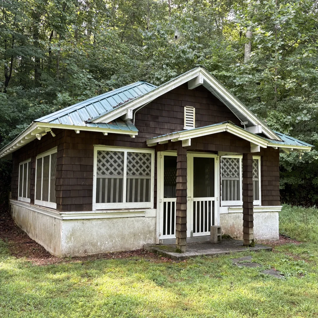Historic springhouse with a green roof surrounded by trees