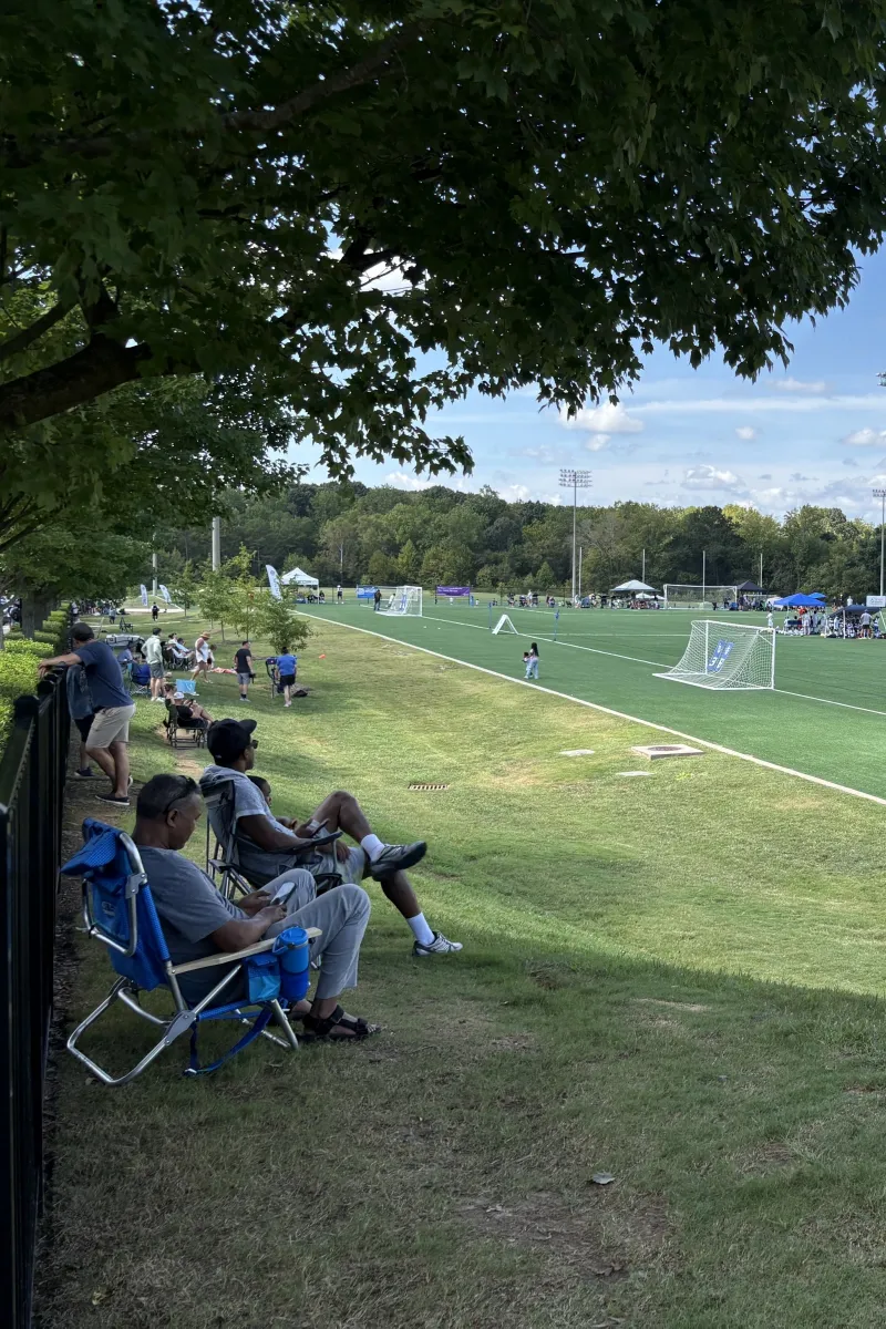 Spectators in lawn chairs watching a game from the sideline at Richard Barry Memorial Park