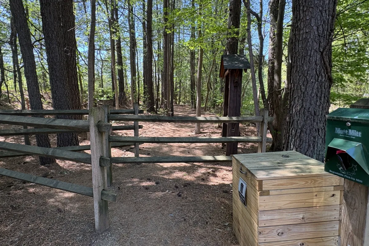 Trailhead entrance with a trash can and dog waste bag dispenser at Buckeye Cove Nature Preserve