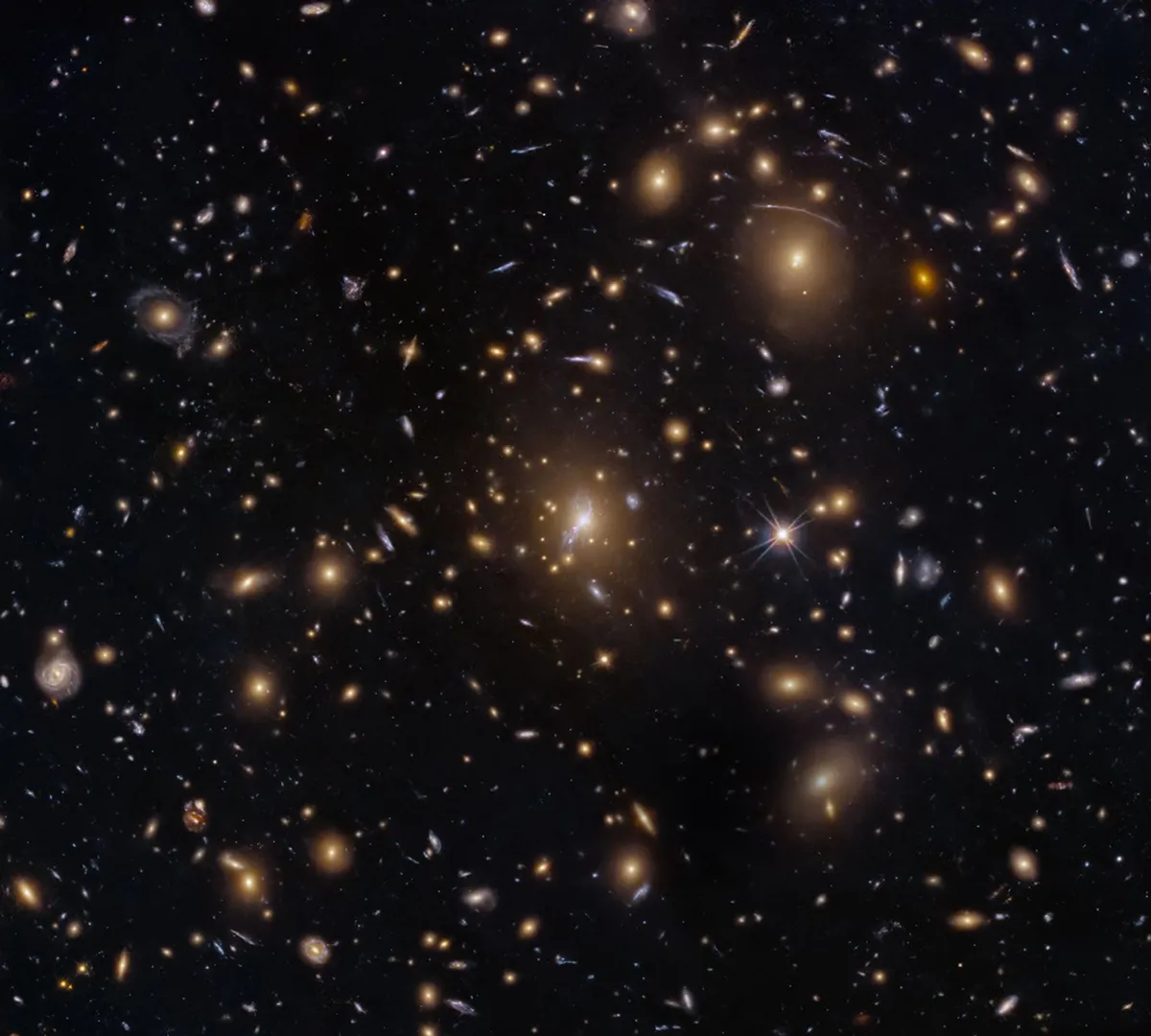 NASA เผยภาพจากกล้องฮับเบิลแสดงกระจุกกาแล็กซี MACS0329-0211 ที่ดูคล้ายฝูงผึ้งรุมล้อมรัง ปรากฏการณ์เลนส์ความโน้มถ่วงช่วยขยายภาพกาแล็กซีไกลโพ้นให้เห็นชัดเจนขึ้น เป็นกุญแจสำคัญในการศึกษาวิวัฒนาการของเอกภพตั้งแต่อดีตกาลจนถึงปัจจุบัน