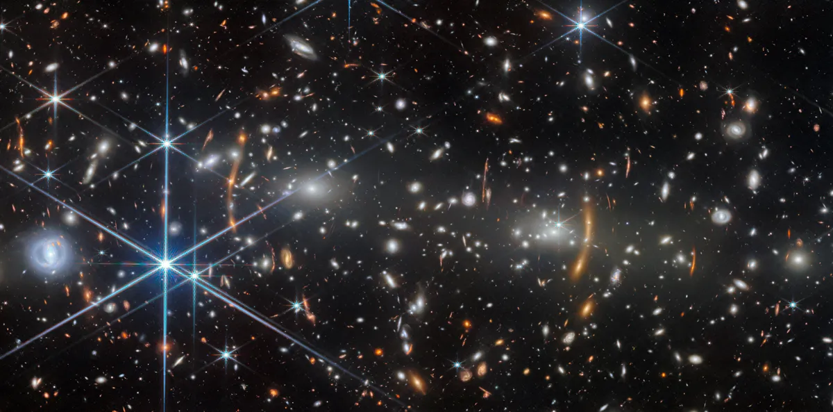 รายงานล่าสุดจาก NASA เผยภาพกระจุกกาแล็กซี MACS J0553.4-3342 จากกล้องเจมส์ เวบบ์ แสดงให้เห็นสภาพเมื่อ 4.4 พันล้านปีก่อน ขณะที่กลุ่มกาแล็กซียักษ์สองกลุ่มกำลังหลอมรวมกันด้วยแรงโน้มถ่วงมหาศาล พร้อมปรากฏการณ์เลนส์ความโน้มถ่วงที่บิดเบือนแสงจากกาแล็กซีห่างไกล