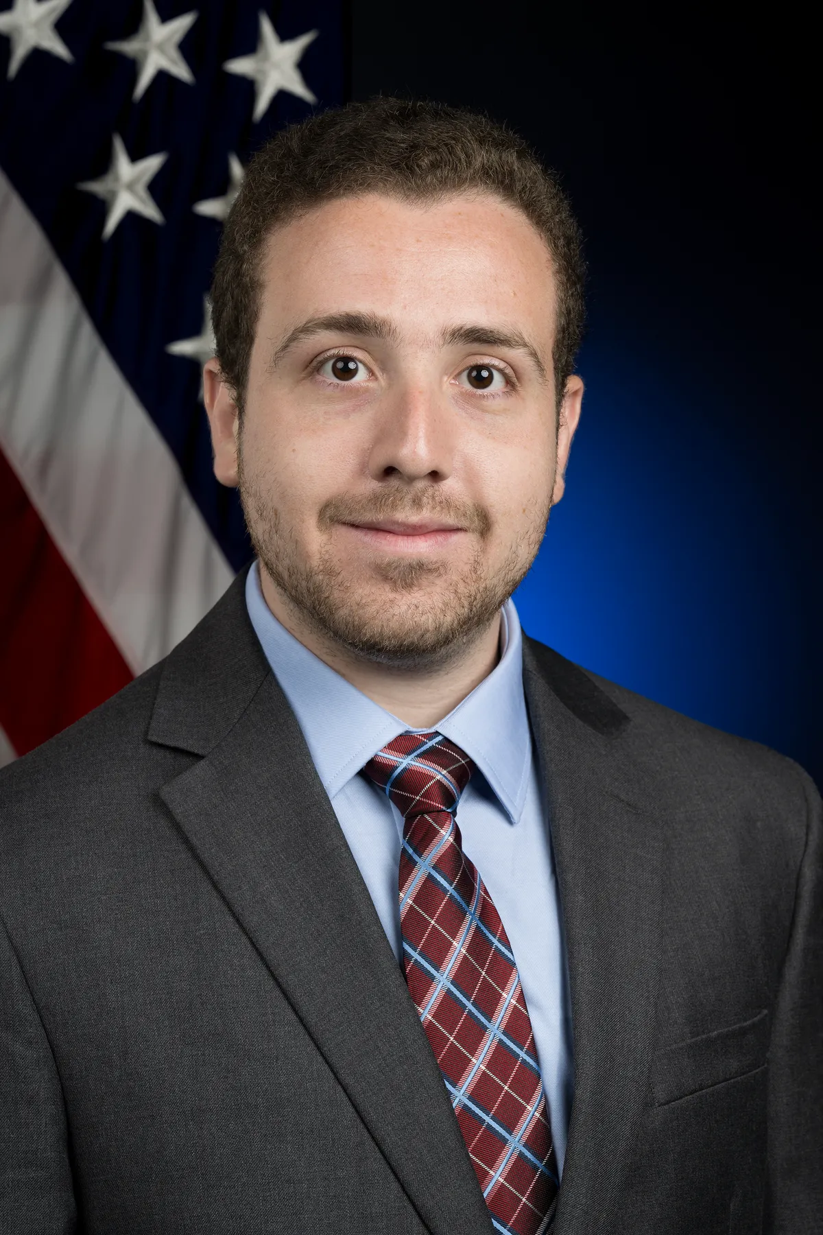 Richard Spolzino วิศวกรการบินและอวกาศของ NASA ยืนอยู่หน้าธงชาติสหรัฐฯ