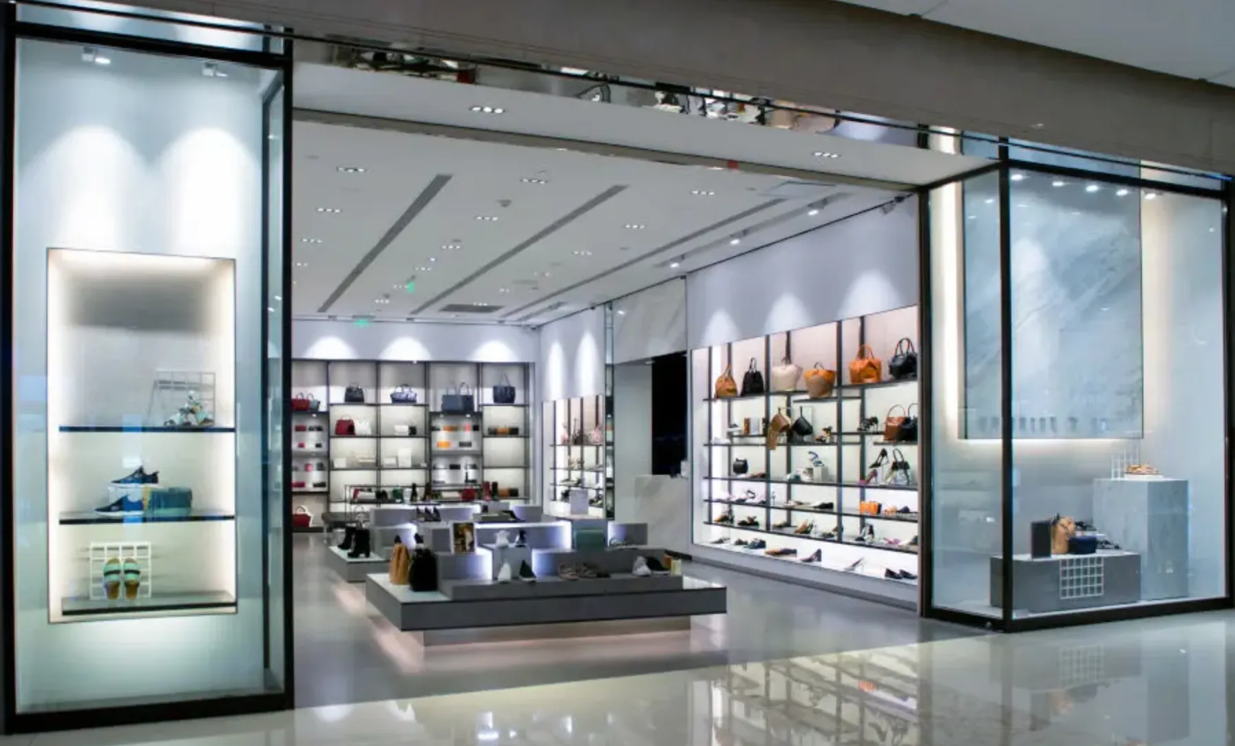Boutique élégante avec étagères lumineuses présentant des chaussures et sacs à main, sol brillant et ambiance moderne.