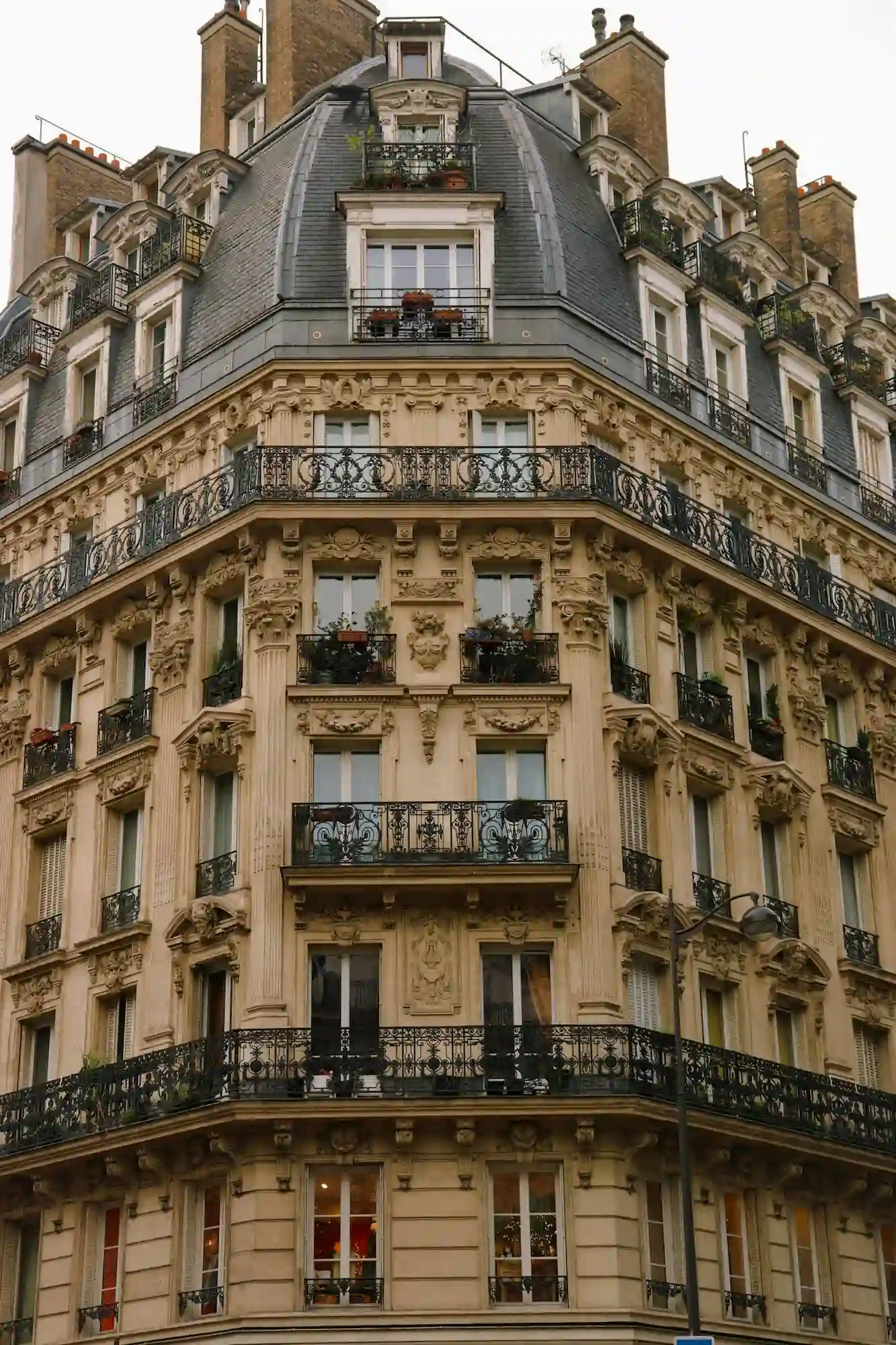 Façade d'un immeuble haussmannien parisien avec balcons en fer forgé et ornements sculptés.