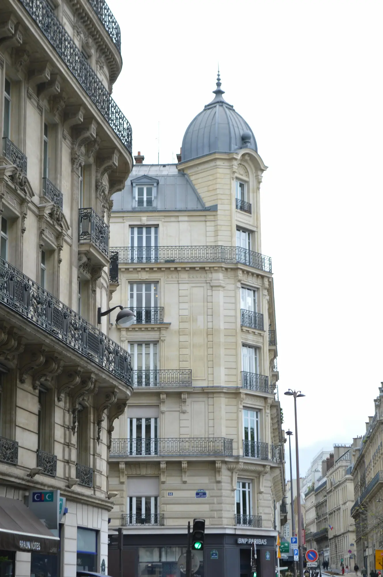 Bâtiments haussmanniens avec balcons en fer forgé et un dôme en zinc au sommet d'un coin d'immeuble à Paris.