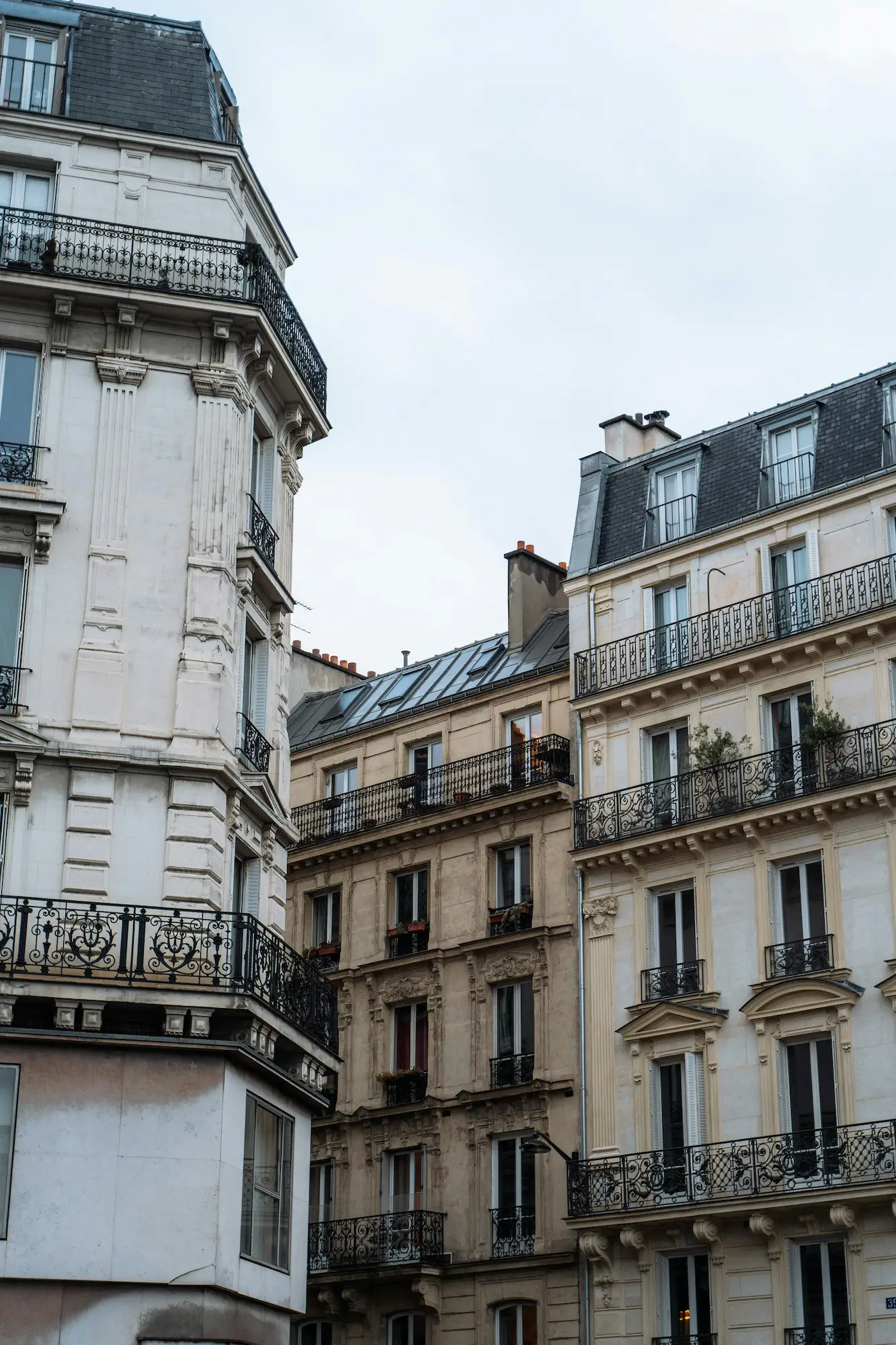 Façades d'immeubles haussmanniens avec balcons en fer forgé sous un ciel nuageux.