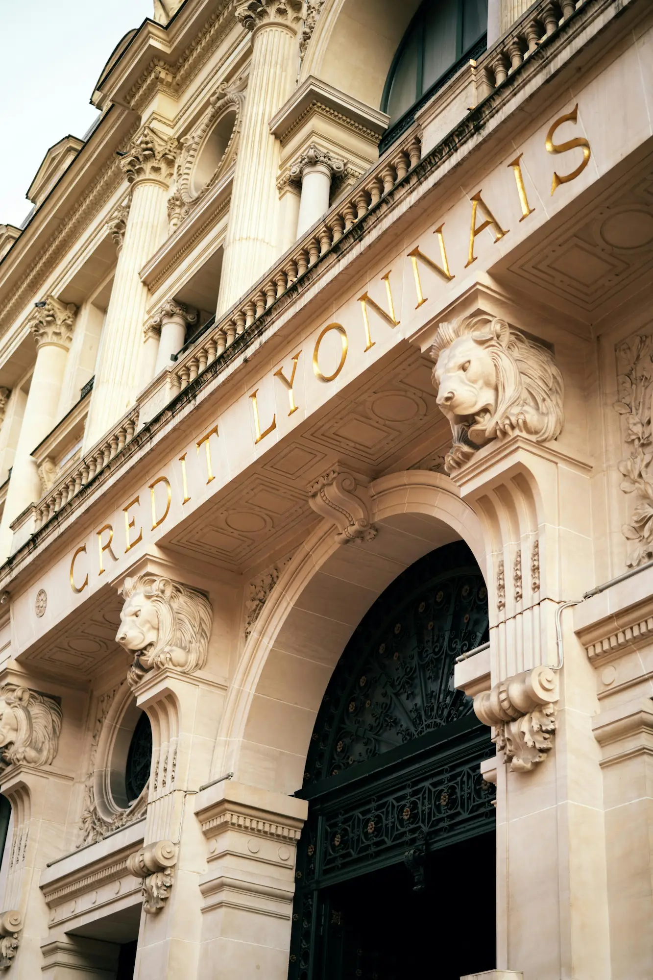 Façade ornée du bâtiment Crédit Lyonnais avec des colonnes classiques et des sculptures de têtes de lion.