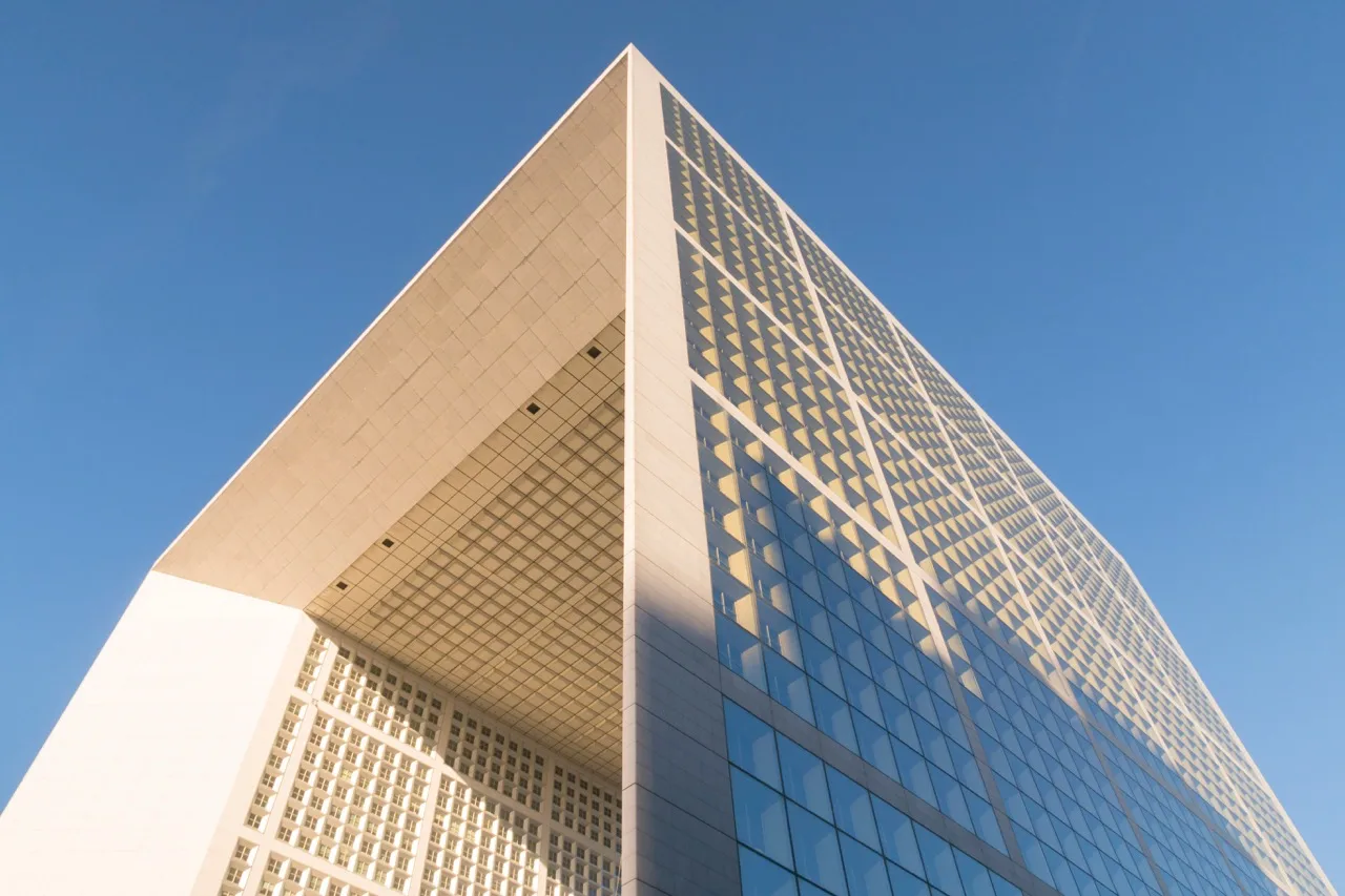 Vue en contre-plongée d'un grand bâtiment moderne avec des façades en verre et un motif géométrique.