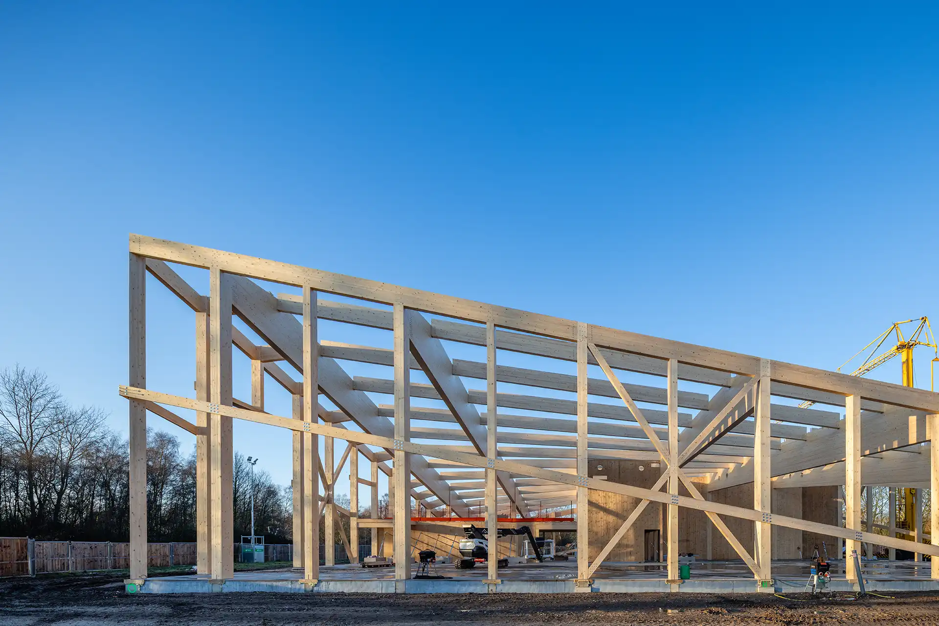 Houten skelet van een industrieel gebouw in aanbouw tegen een heldere blauwe lucht.