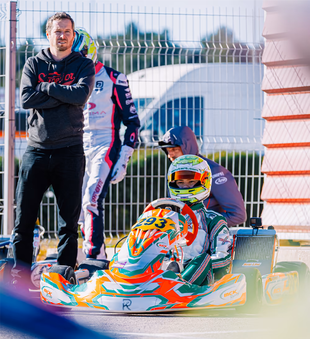 MCK Racing driver in the kart with a team member on the grid in Valencia