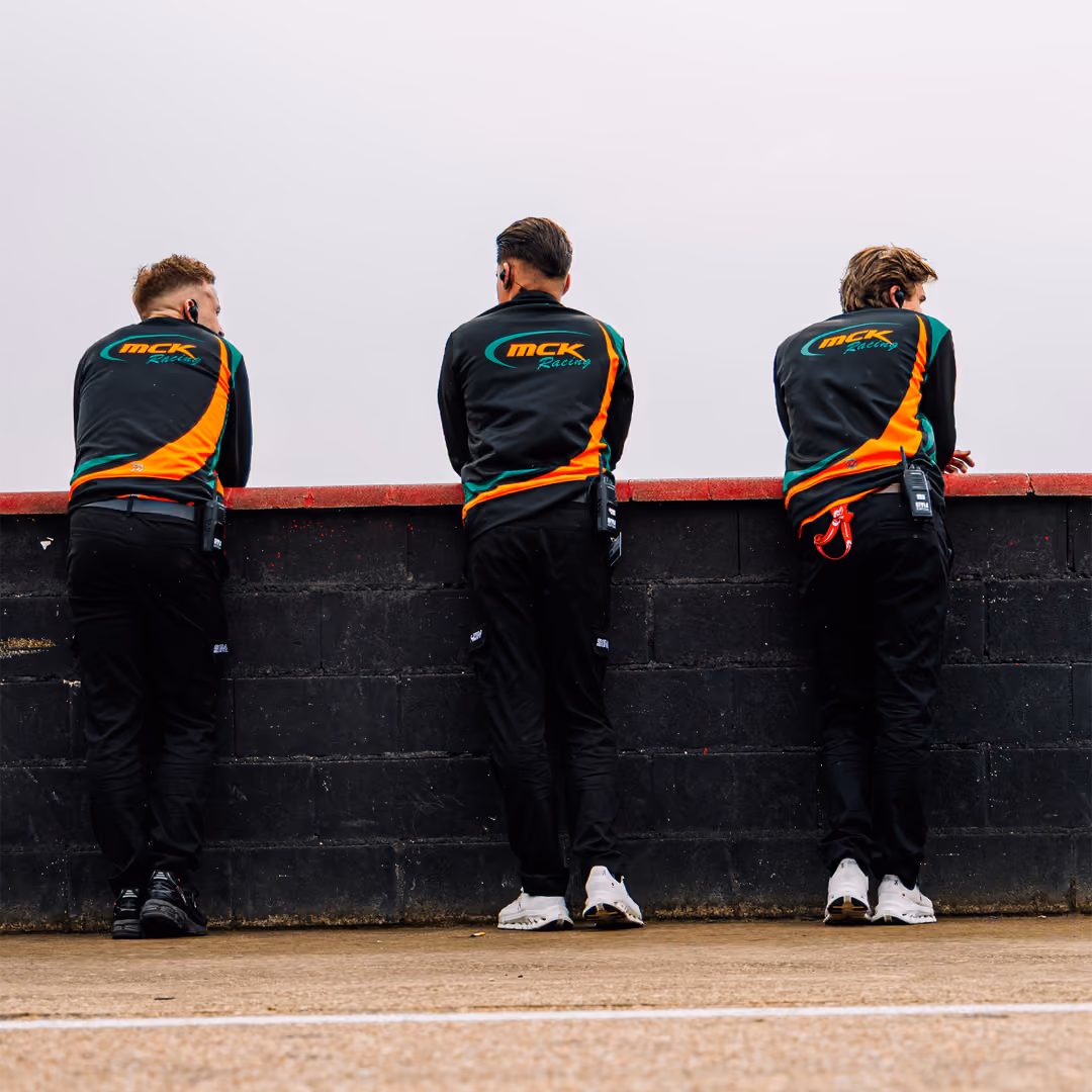 Three MCK Racing team members watching from the pit wall in Zuera