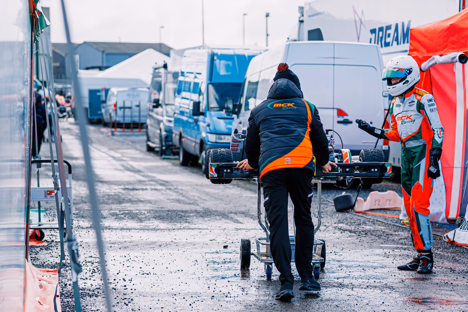 MCK Racing mechanic pushing a kart trolley through the paddock