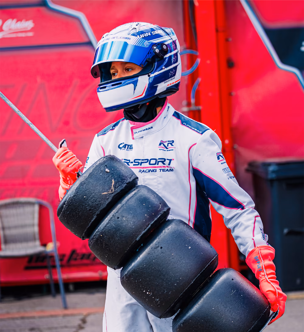 Driver carrying kart tyres in the paddock in Mariembourg