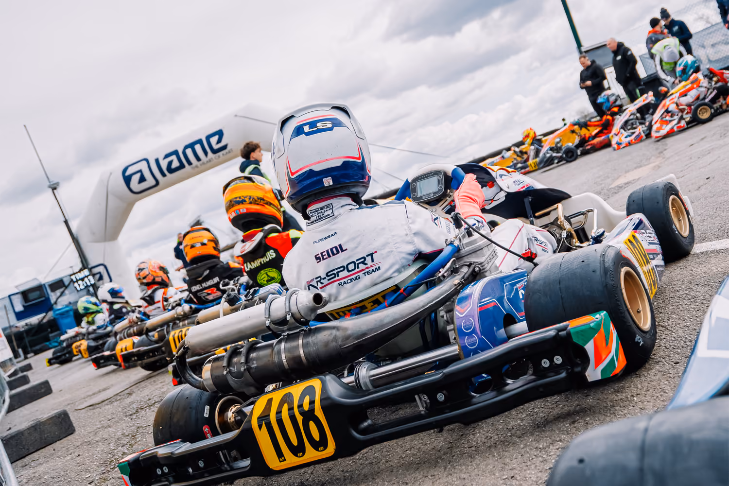 Karts in parc fermé under the IAME arch in Mariembourg