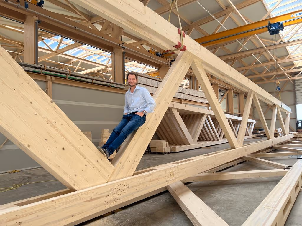 Martin Hilger sitzt zwischen Holzbalken während des Neubaus