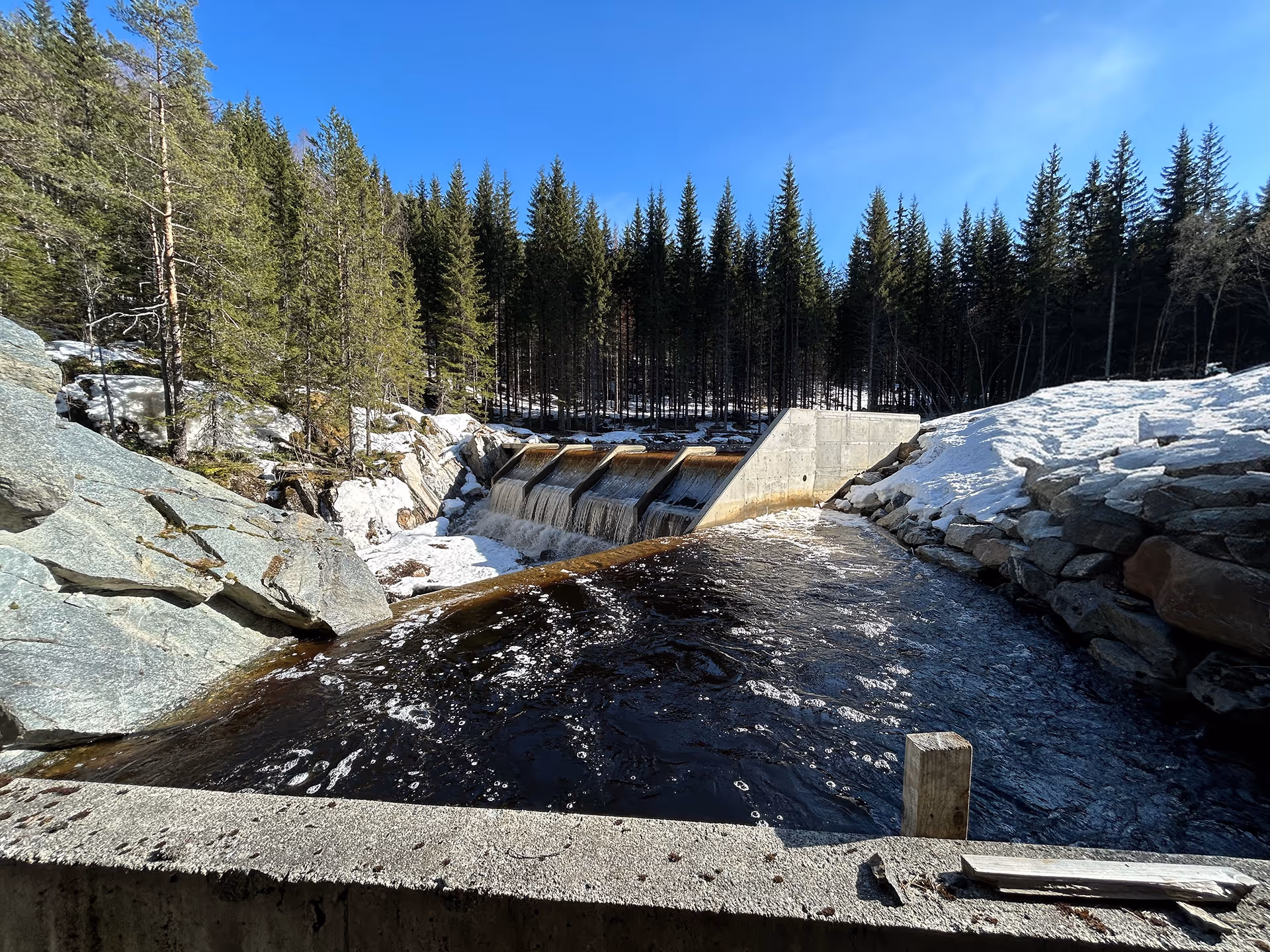 Flussstauwehr in einem bewaldeten Gebiet mit Schnee