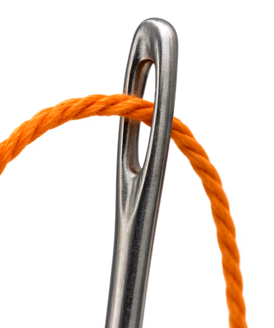 Close-up of a silver sewing needle with an orange thread passing through its eye.