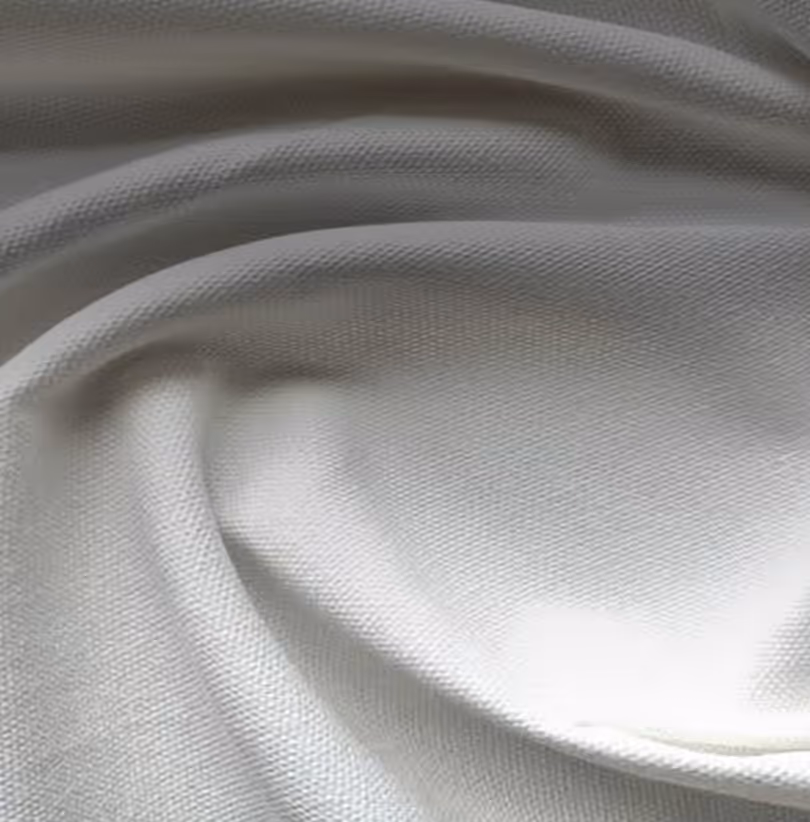 Close-up of soft, cream-colored, textured woven fabric with folds.