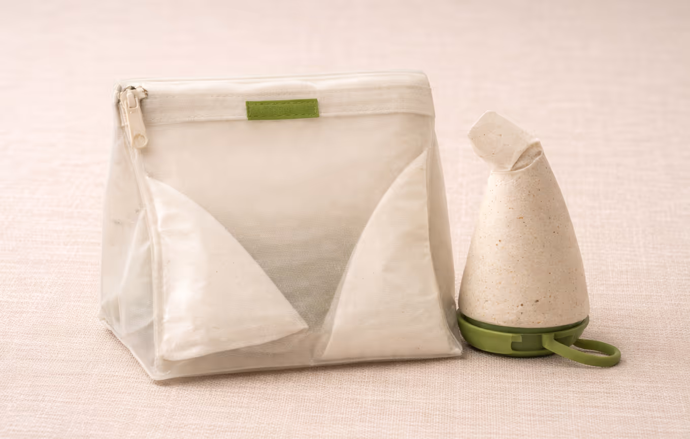 Clear reusable pouch with cloth items inside and a cone-shaped natural sponge or scrub on a green base.