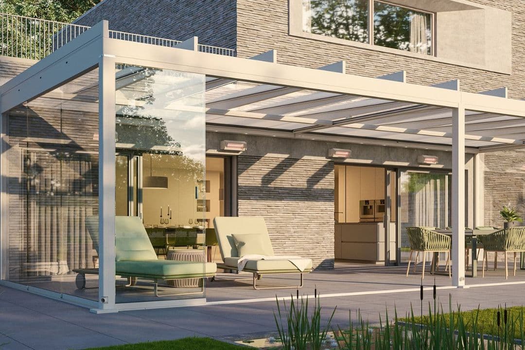 Moderner Wintergarten mit verglastem Rahmen, zwei grünen Liegestühlen und einem Sitzbereich, angrenzend an ein Haus mit Steinmauer.
