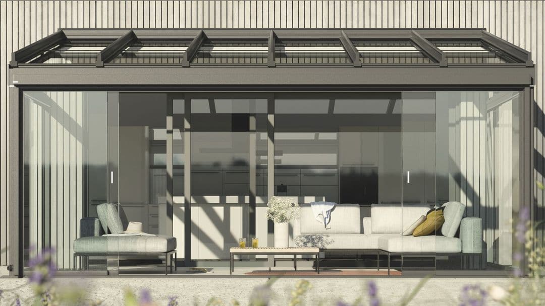 Moderner Wintergarten mit großem Glasschiebetürsystem, bequemen Sofas und einem Tisch mit Blumenvase und Getränken.