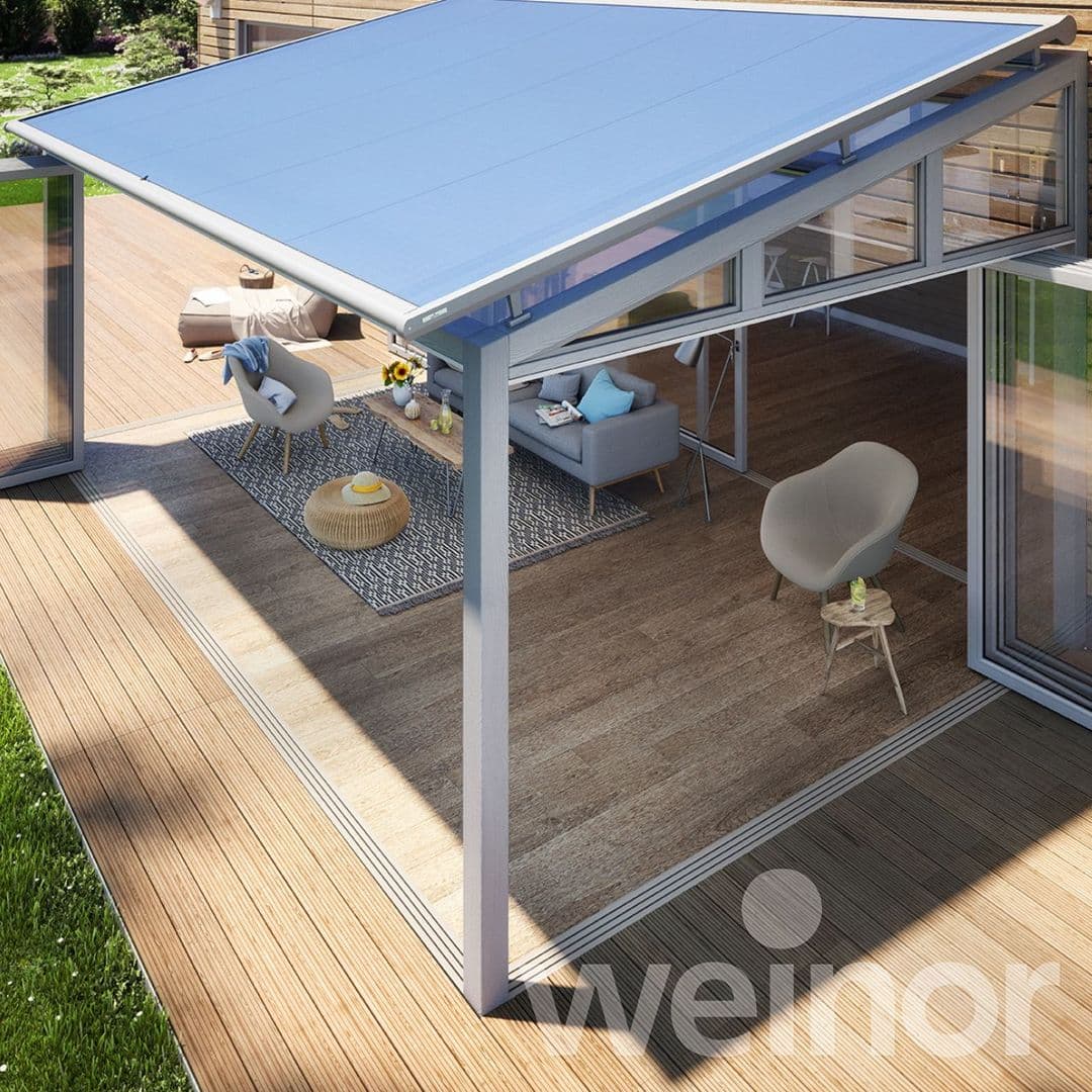 Moderner Außenbereich mit hellblauem Sonnenschutz an Glasüberdachung über gemütlicher Sitzecke mit Stühlen und Sofa.
