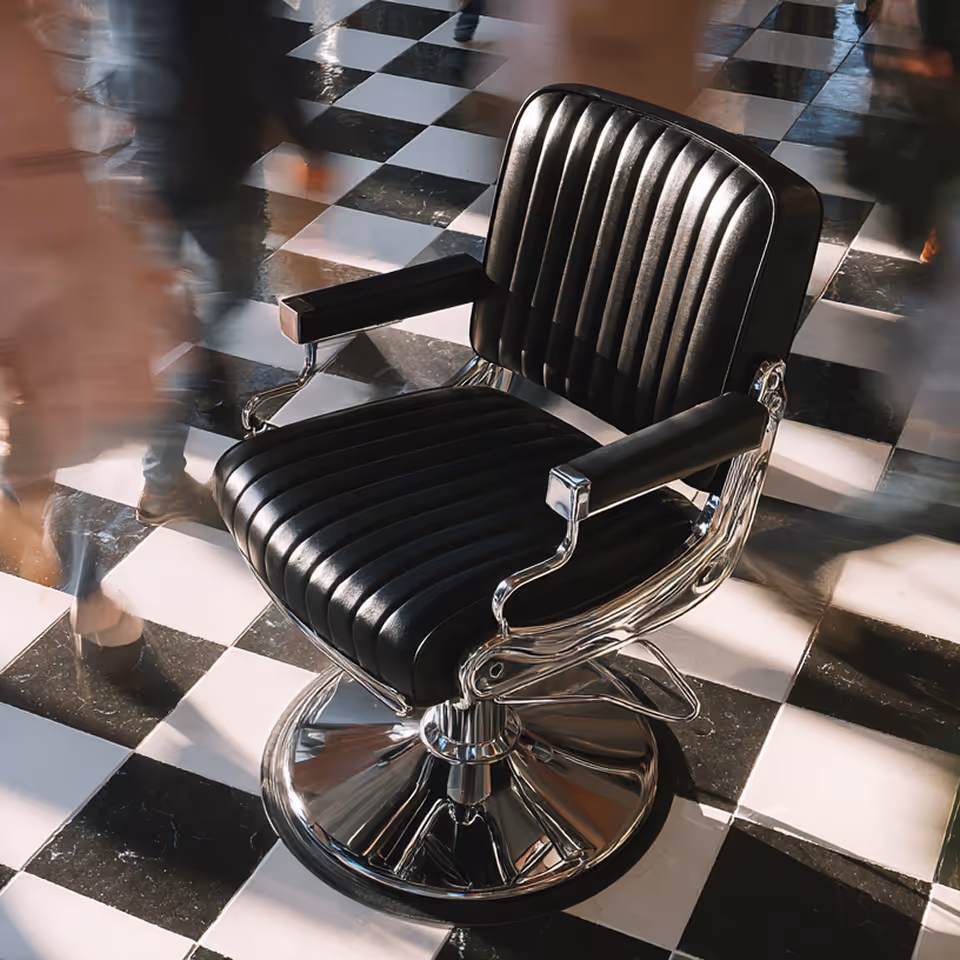 Silla de barbero negra con base de metal en un suelo de baldosas a cuadros en blanco y negro, con personas borrosas caminando alrededor.