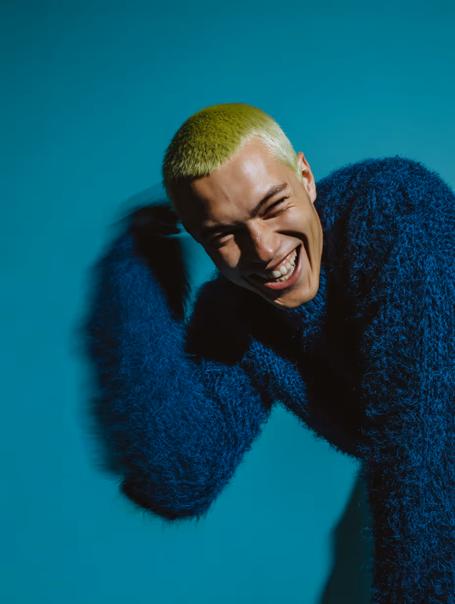 Close-up of lips with glossy maroon lipstick and hands with matching maroon pointed nails touching the chin.