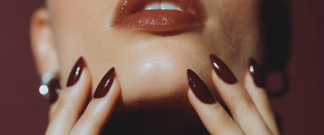 Close-up of a hand with glossy white almond-shaped nails against a light background.