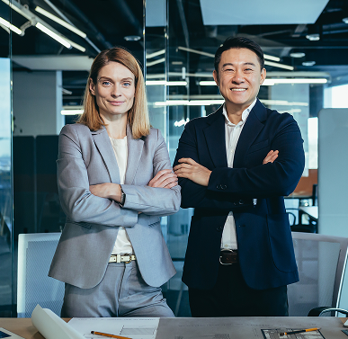 Two business professionals standing with arms crossed in a modern office.