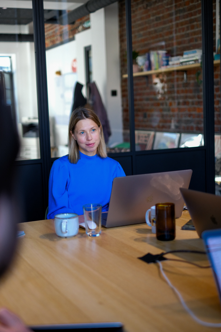 Een jonge vrouw staart naar haar computerscherm tijdens een teammeeting.